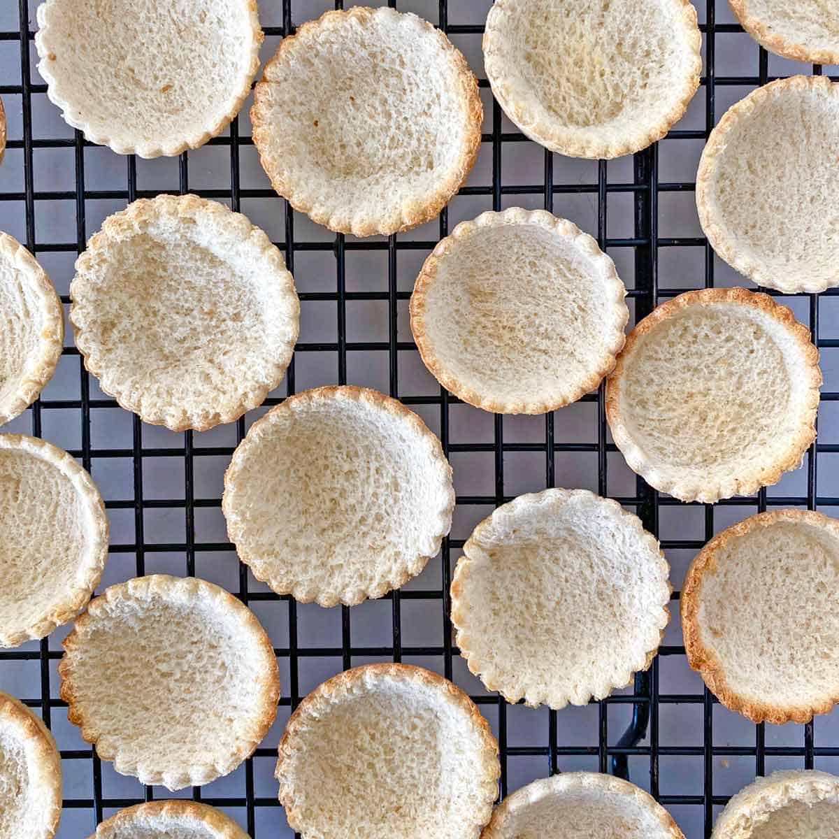 Just-baked toast cups cooling on a wire rack.