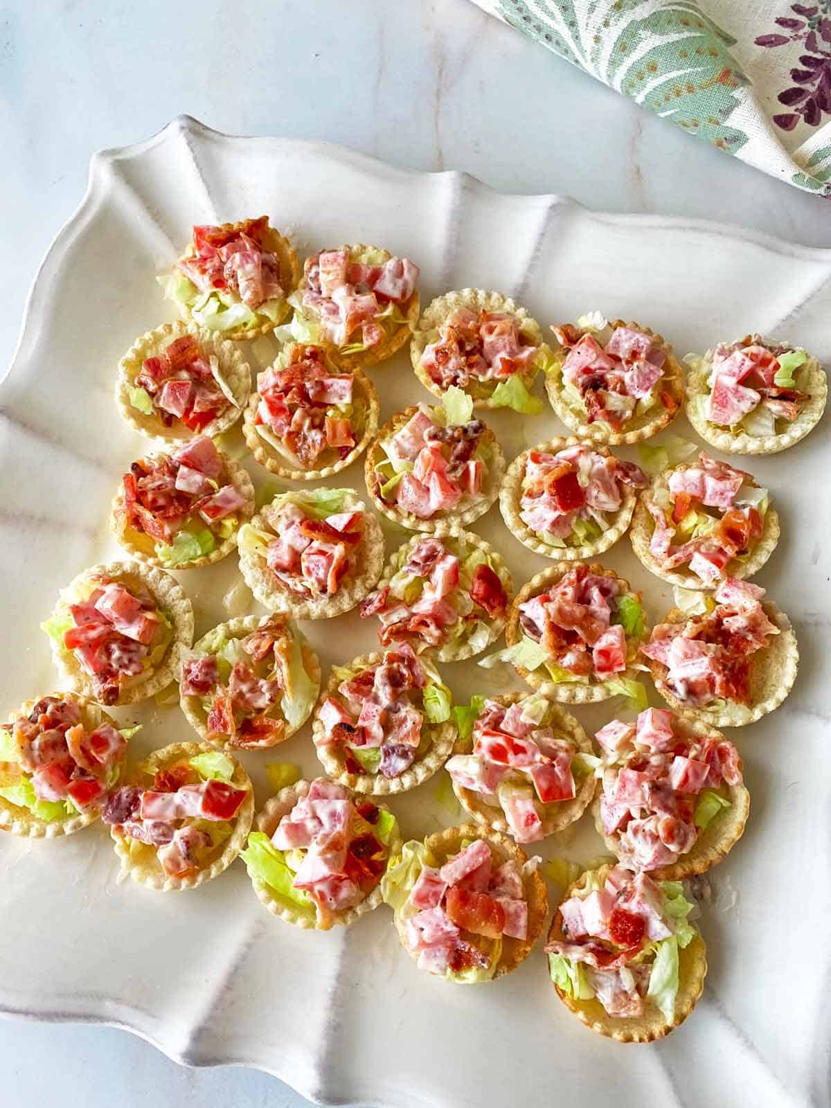 Two dozen mini BLT cups on a white platter ready to serve.