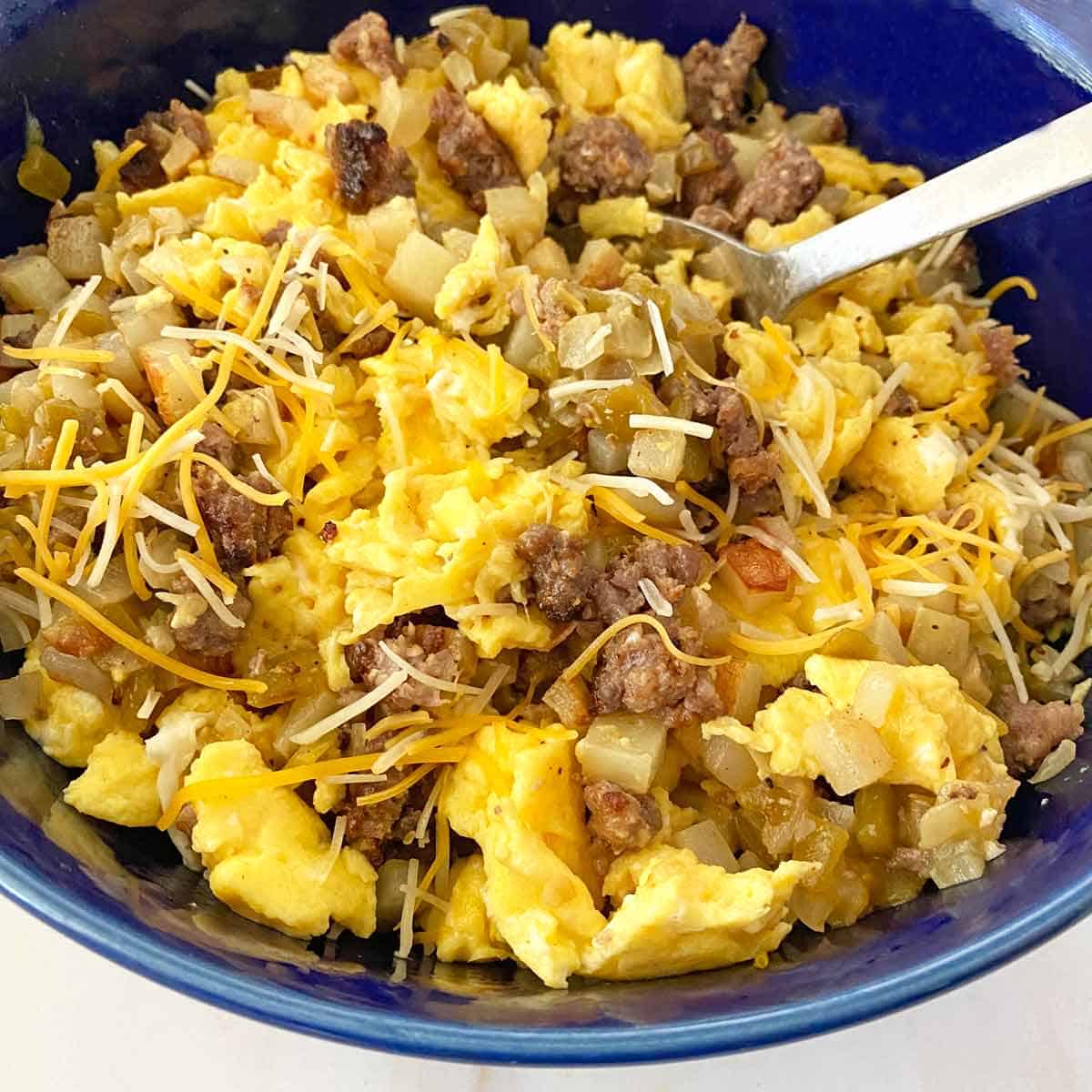 Stirring together cooked burrito filling ingredients in a large bowl.