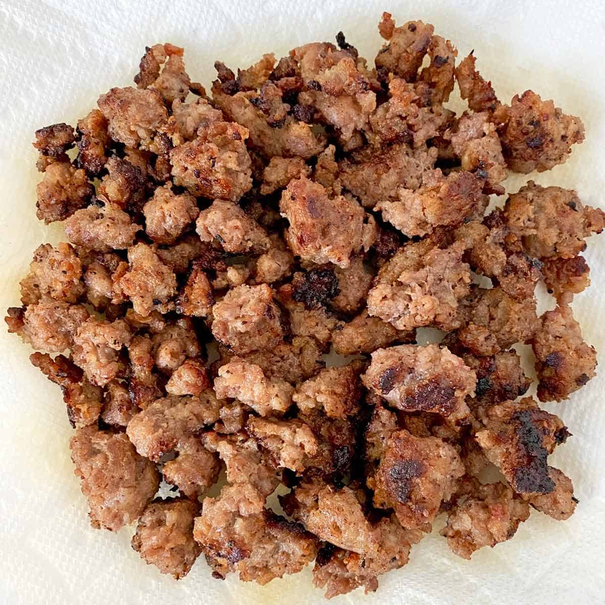 Cooked, crumbled breakfast sausage draining on paper towels.