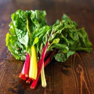 Colorful just-picked chard on a wood table.