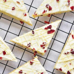 Six cranberry bliss bars on a black cooling rack.