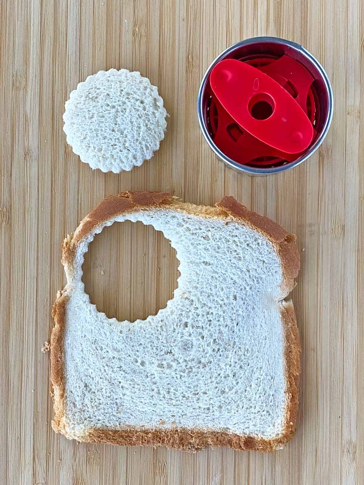 Using a scalloped round cutter to cut a circle from a piece of flattened bread.