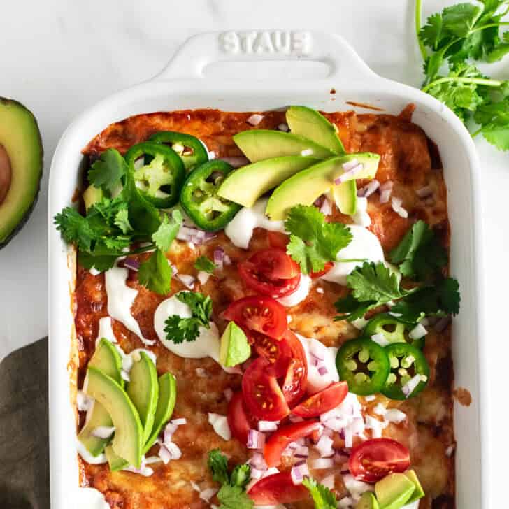 Chicken enchiladas garnished with avocado and jalapenos.