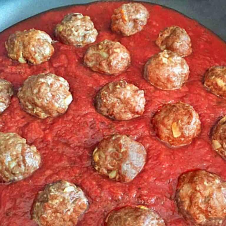 A batch of cooked Italian meatballs in a skillet with spaghetti sauce.