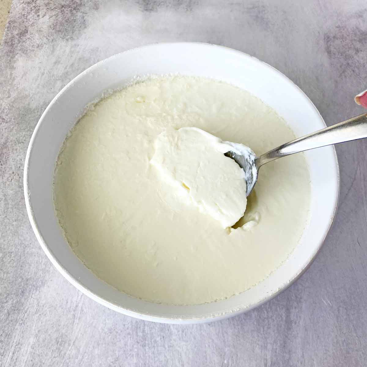 A spoon inserted in a dish of fresh homemade yogurt.