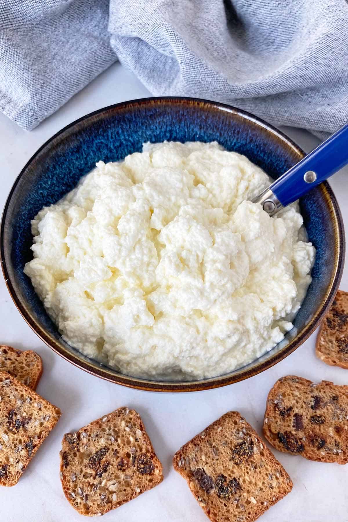 Ricotta cheese next to some crackers for serving. 