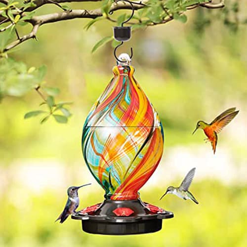 A blown glass hummingbird feeder with three hummingbirds.