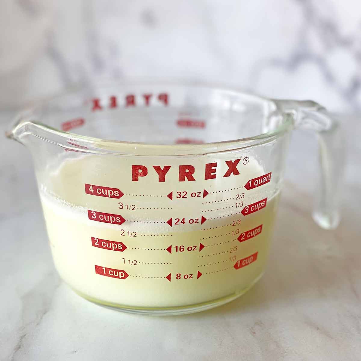 A Pyrex cup filled with 3 cups of leftover whey from making ricotta cheese.