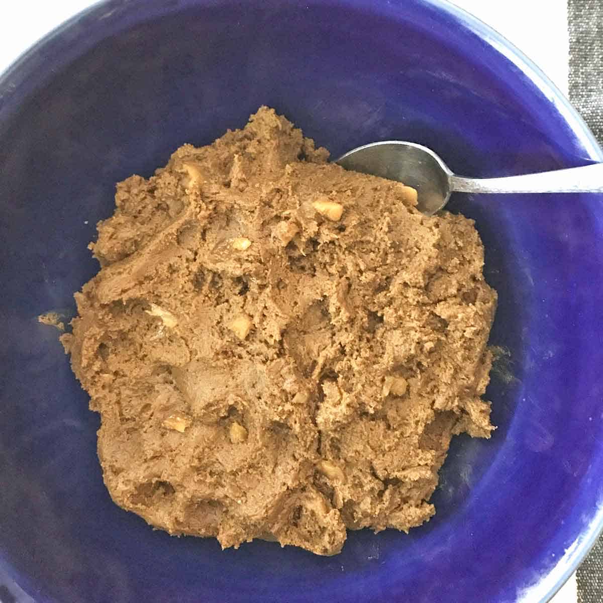 A blue bowl filled with cookie dough to make molasses crinkle cookies.