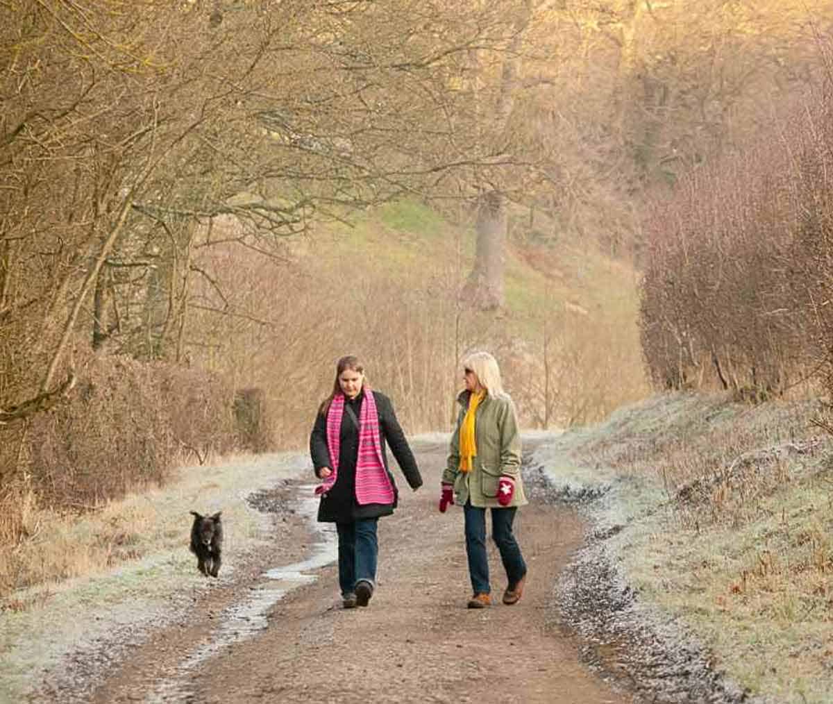 A mother and daughter walking a dog.