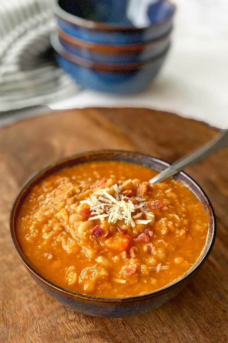 Navy bean soup with bacon in a black bowl.