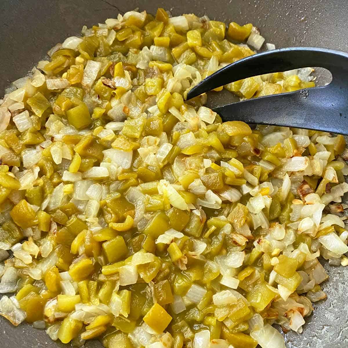 Cooking chopped onions and green chiles in a skillet.