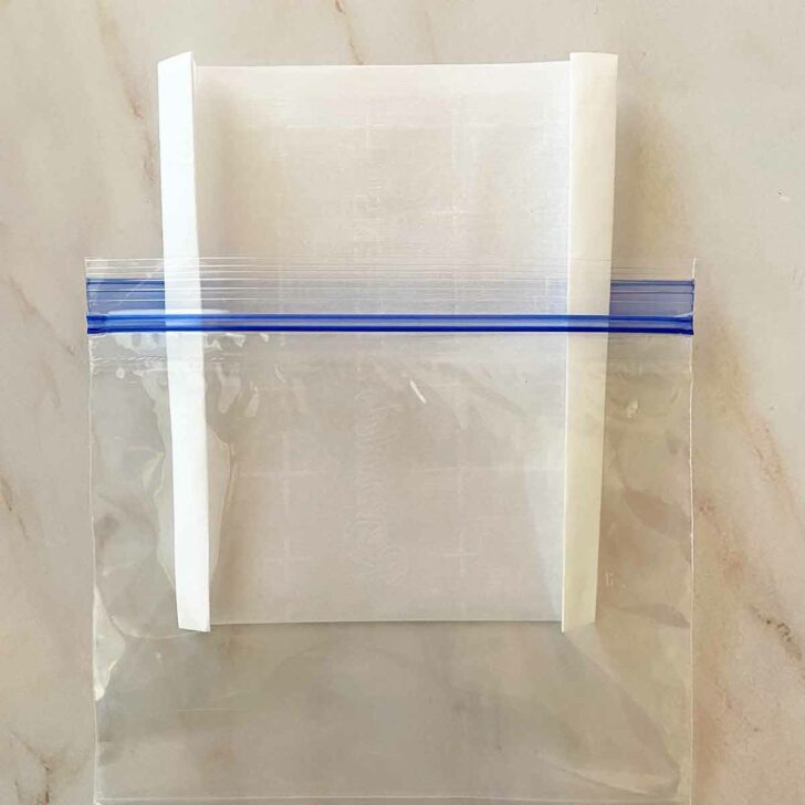 Folding parchment paper to fit inside a plastic zip top freezer bag.