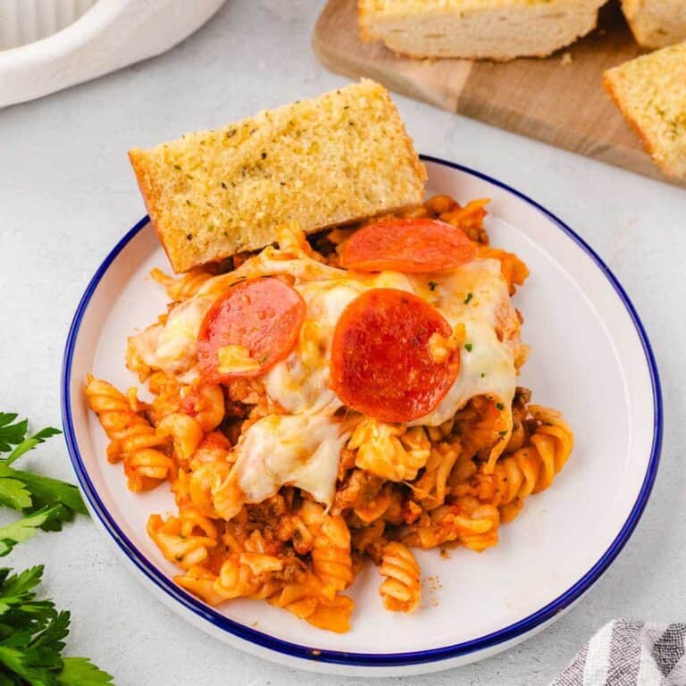 A serving of pizza pasta bake with garlic bread.