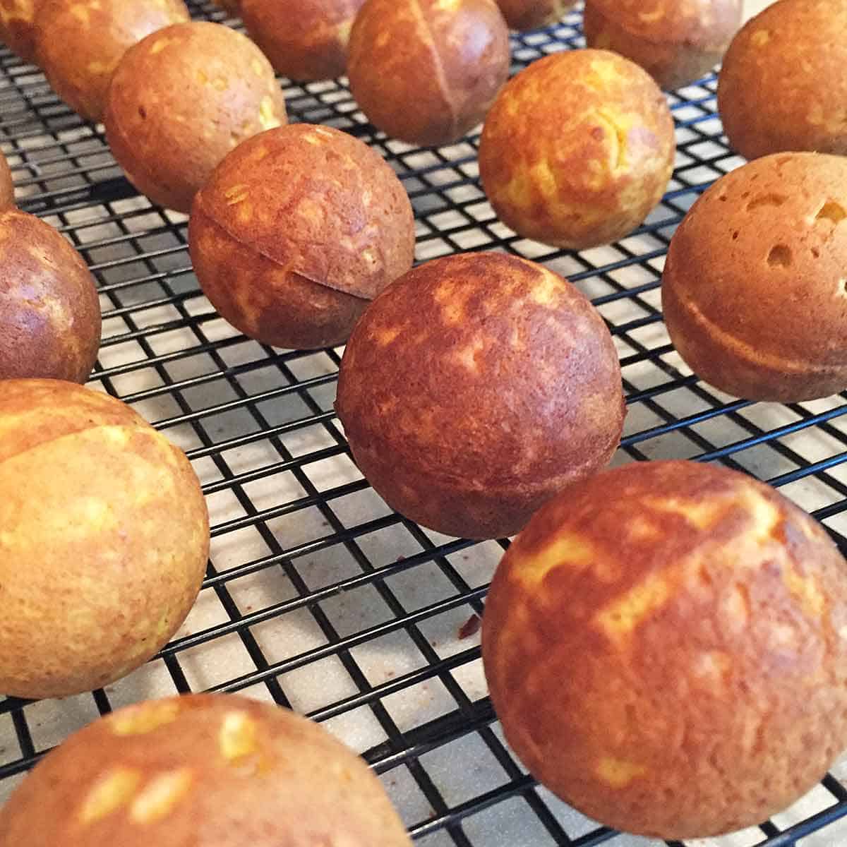 Donut holes cooling on a wire rack.