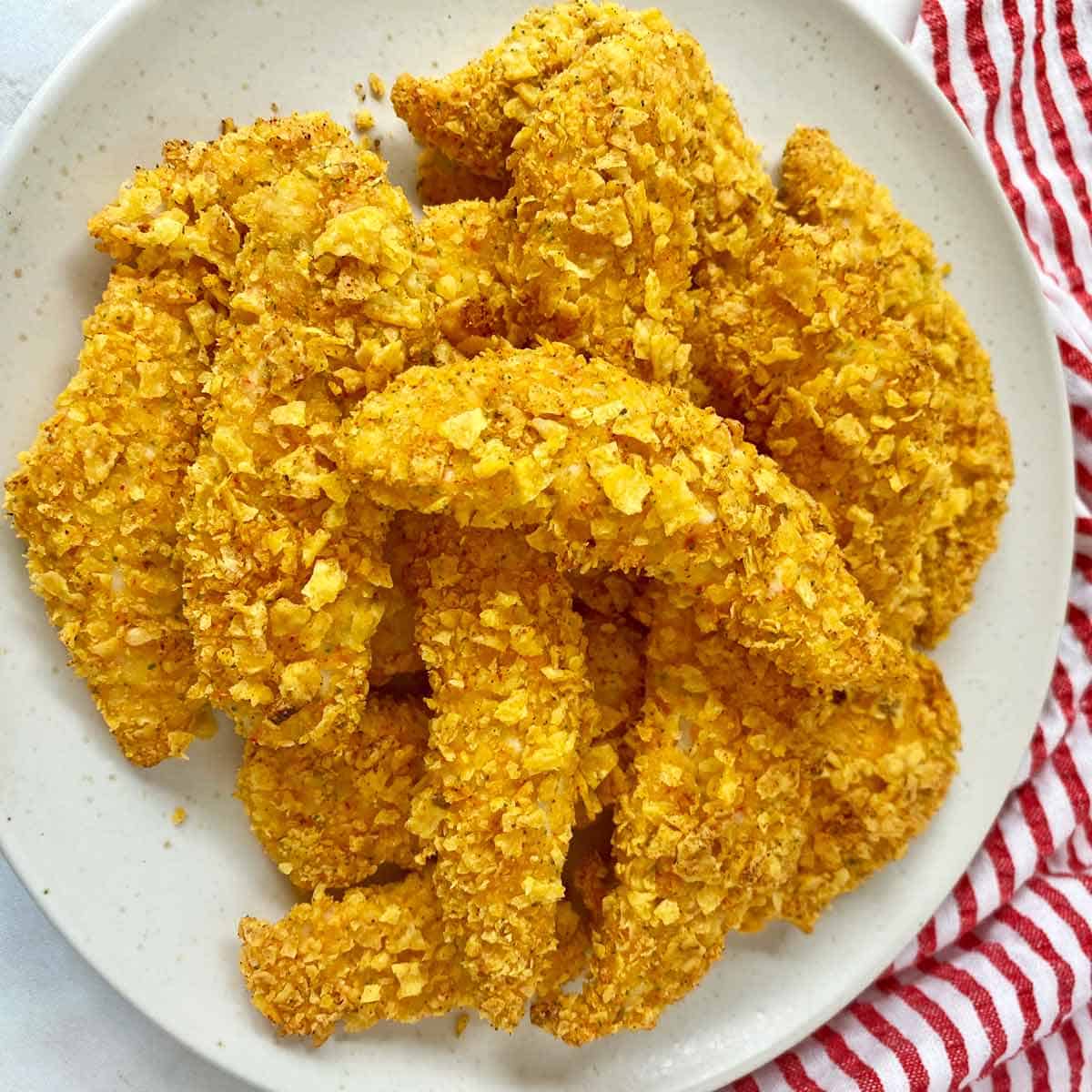 Golden brown cooked Doritos chicken tenders on a serving plate.