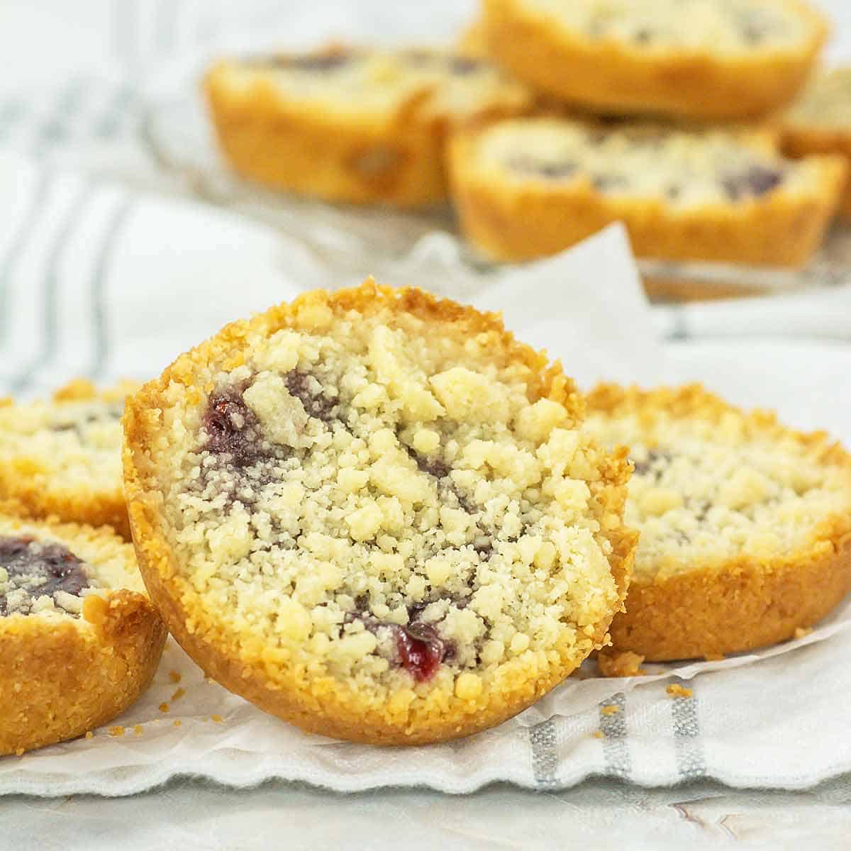 Close up of a raspberry crumble cookie with more stacked up behind it.