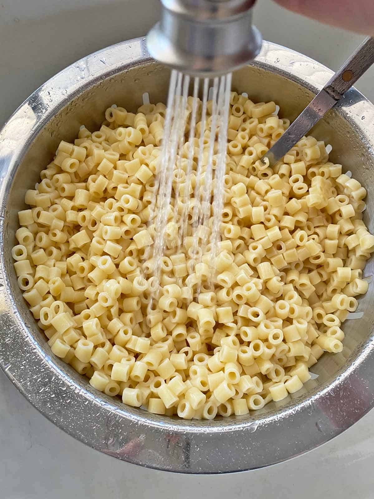 Rinsing cooked macaroni with water.