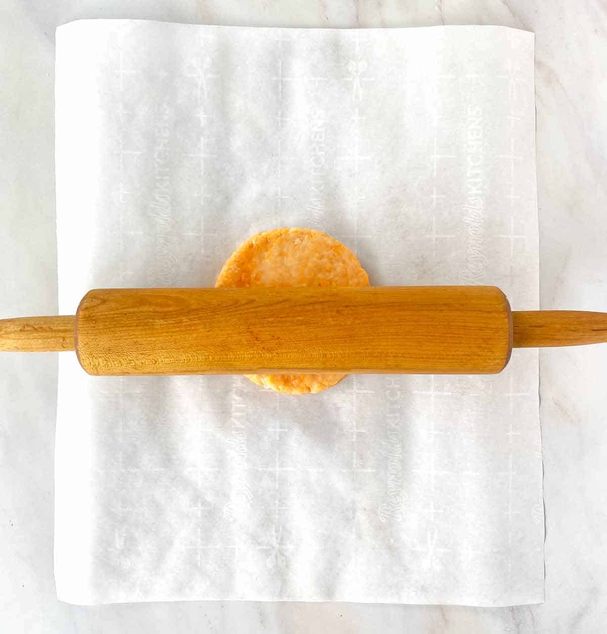 Beginning to roll cheese cracker dough with a wood rolling pin.