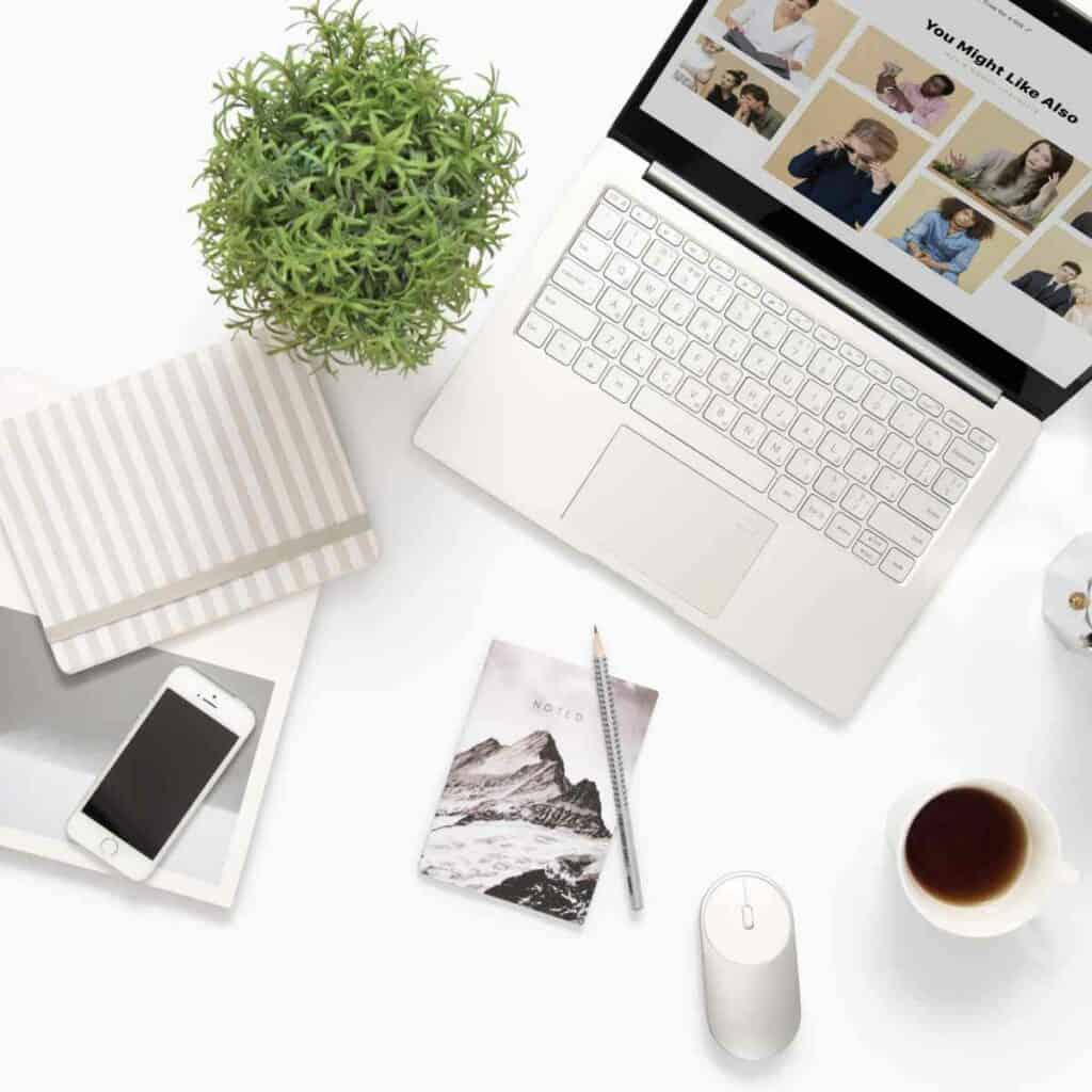 A tidy desk with a laptop, cup of coffee, and plant.