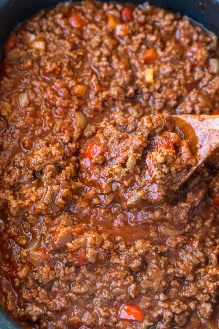 A wooden spoon stirring sloppy joe mixture.