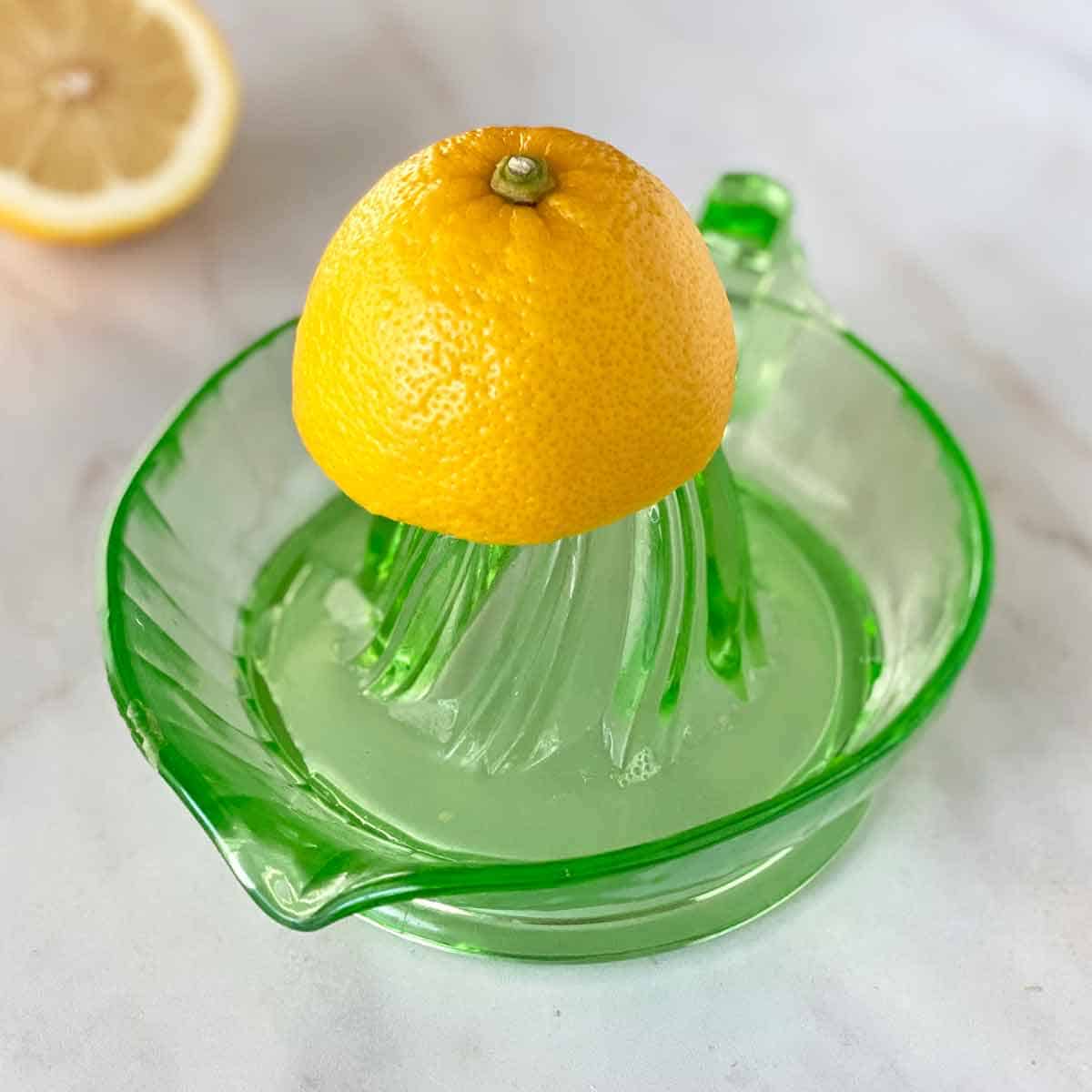 Lemon half sitting on top of a green glass lemon juicer. 