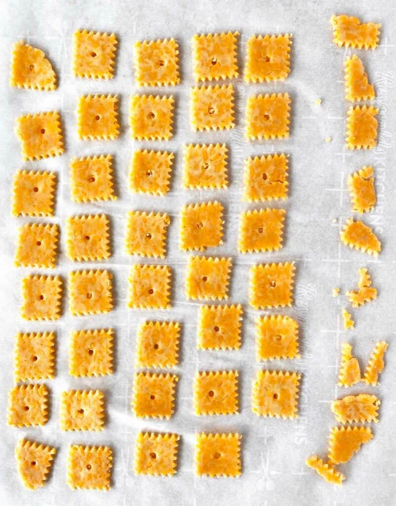 Unbaked cheese crackers on parchment paper, ready to bake.