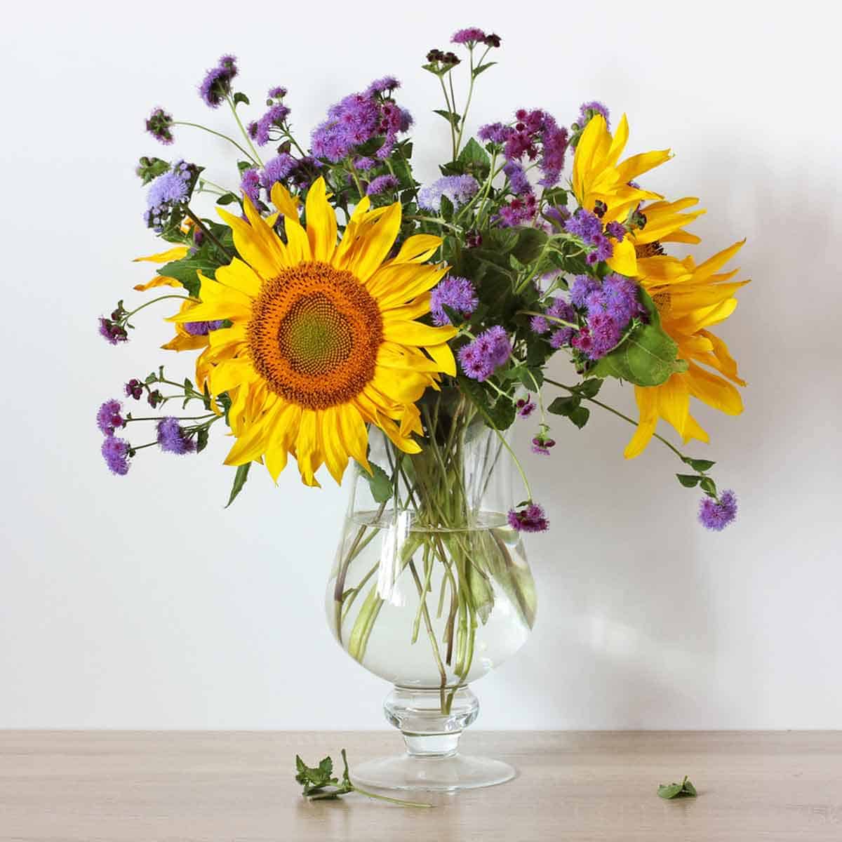 A glass vase filled with sunflowers and wildflowers.