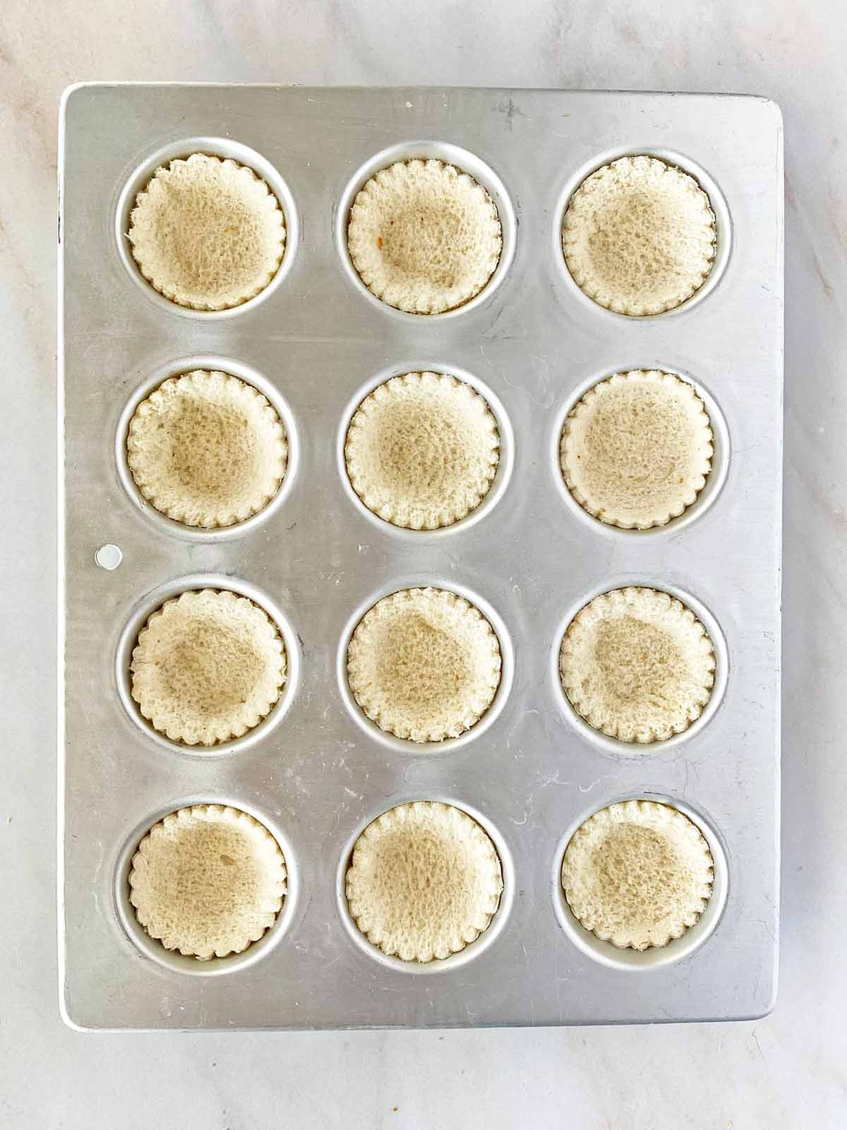 12 bread rounds pressed in a mini muffin tin.